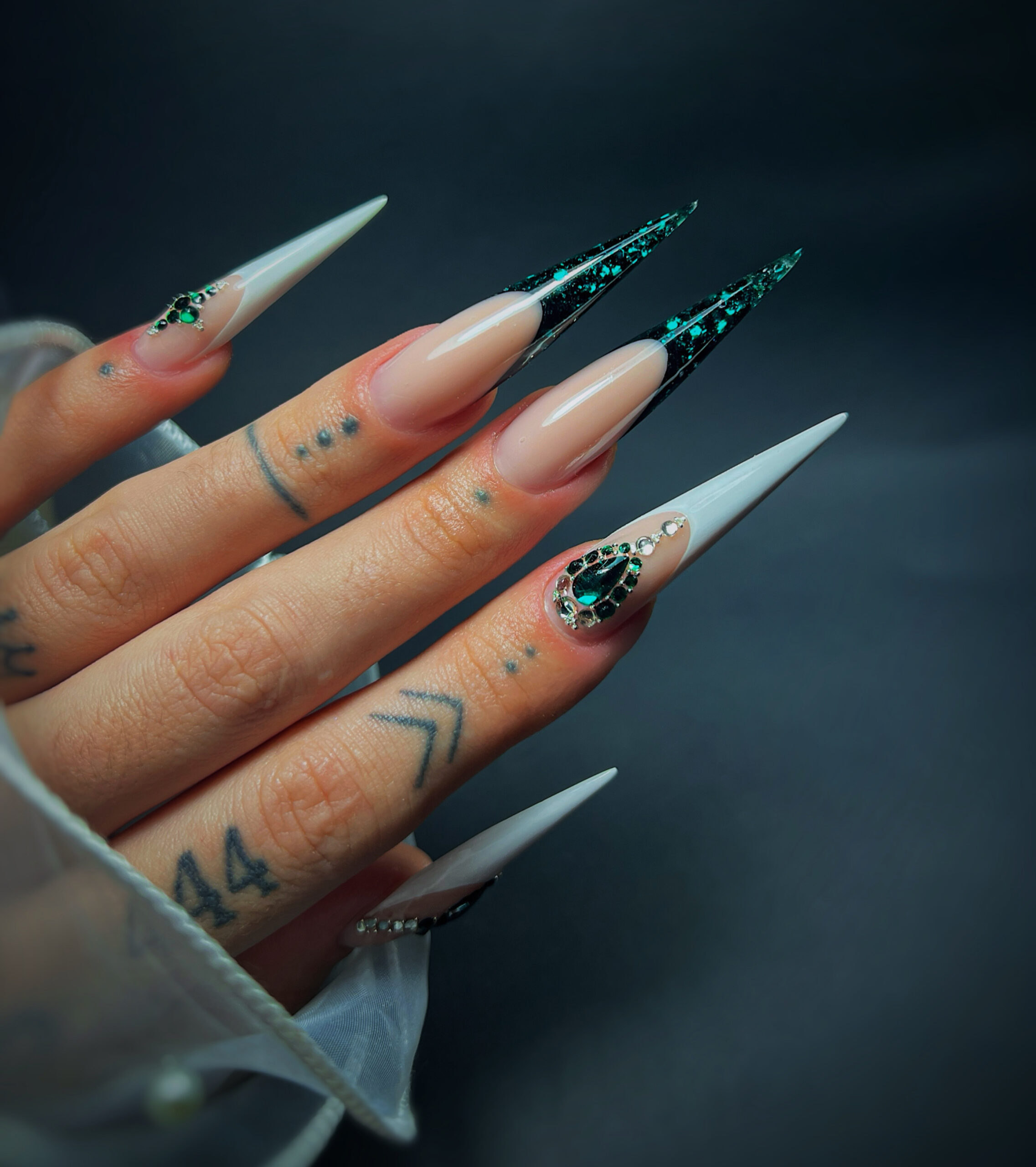 Podaljšani stiletto nohti s smaragdno zelenim vzorcem in kamenčki, delo studia Dior Nail Studio
